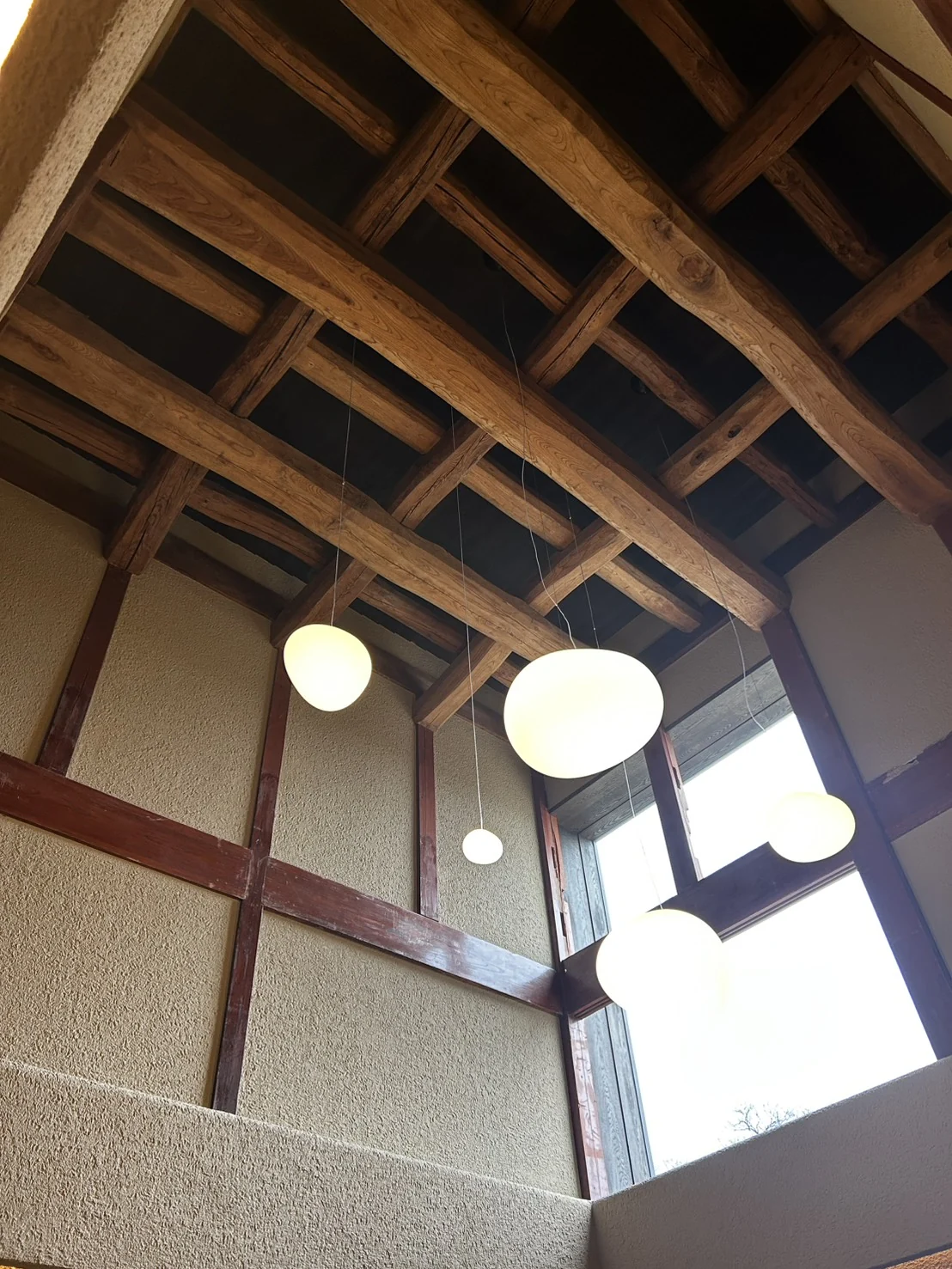 木の梁と複数の照明を見上げた吹き抜け空間